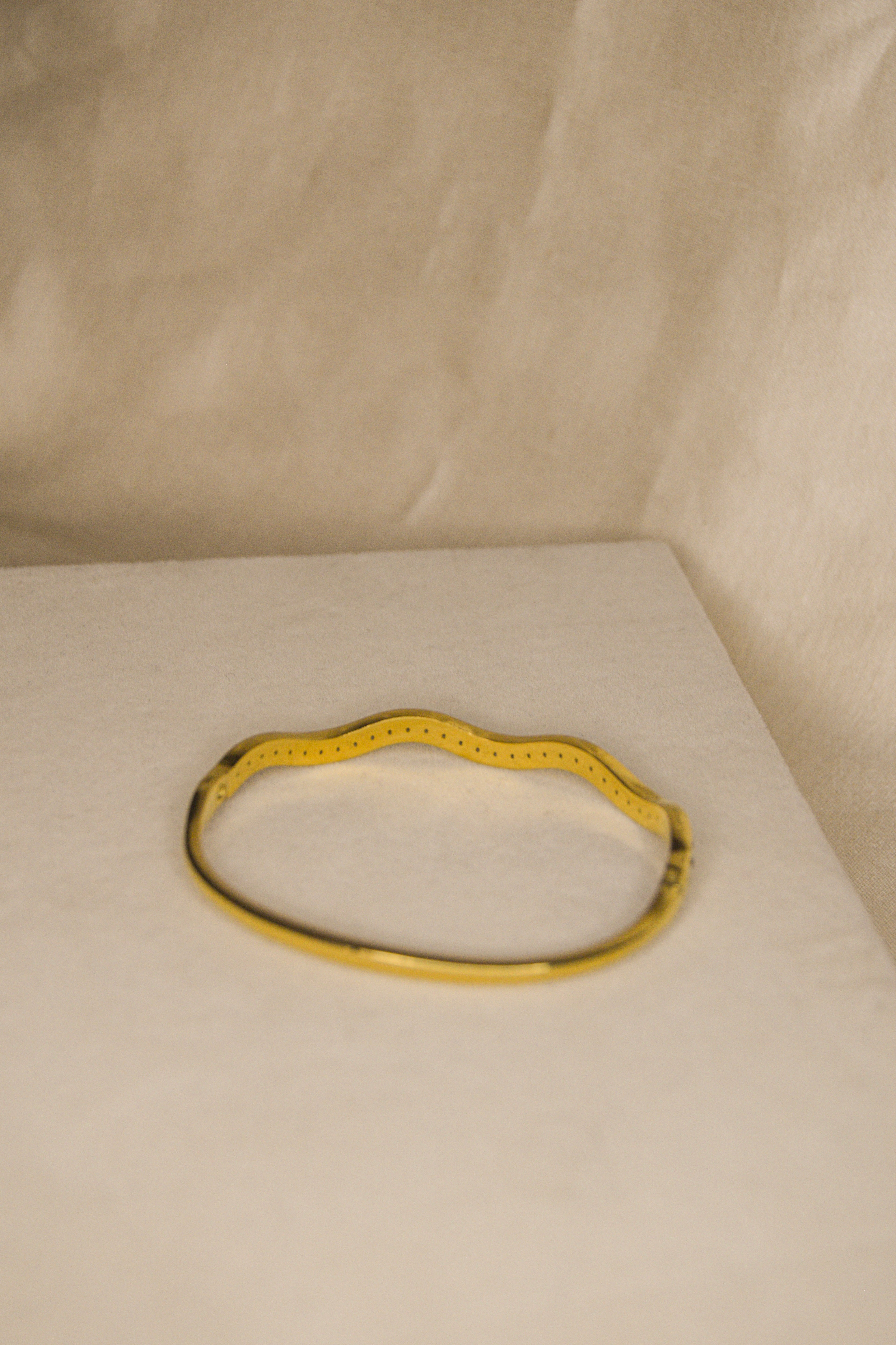 Pulseira dourada com ondas brilhantes